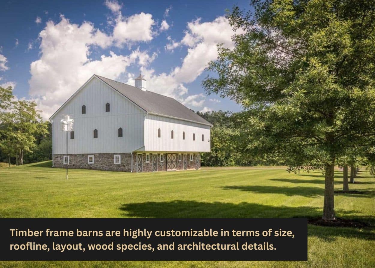 Large white timber frame barn in open grassy field with trees.