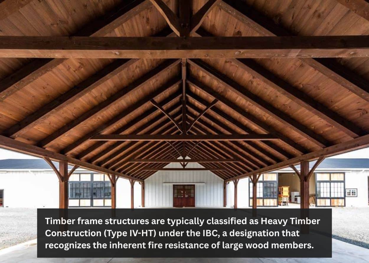 Interior view of a timber frame barn showing exposed wooden trusses and beams constructed to meet Pennsylvania building code requirements. Caption: Timber frame structures are typically classified as Heavy Timber Construction (Type IV-HT) under the IBC, a designation that recognizes the inherent fire resistance of large wood members.